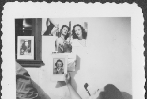 Man laying on cot looking at pictures of women (ddr-densho-434-421)
