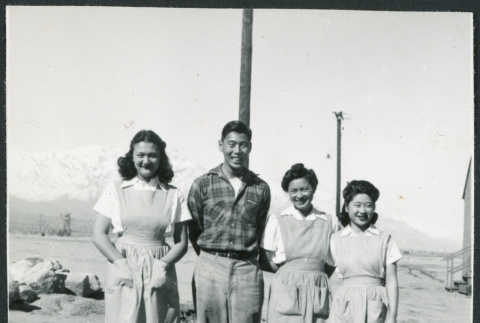 Photograph of four people standing in front of a utility pole with the Sierra Nevada in the background (ddr-csujad-47-187)