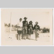 Three women in civilian clothes posing with uniformed officer (ddr-densho-223-11)