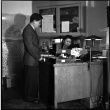 Man standing next to desk, woman seated at desk (ddr-densho-426-951)