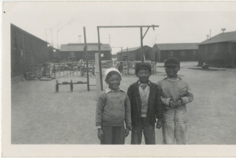 Three boys standing in front of a playground (ddr-manz-7-13)