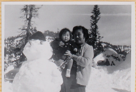 Yoshiko Shiomi holding Susan Shiomi next to snowman (ddr-densho-522-240)