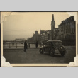 Car at river's edge with bridge and clock tower in background (ddr-densho-466-787)
