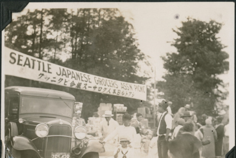 Group of people under banner for Seattle Japanese Grocers Assn Picnic (ddr-densho-483-547)