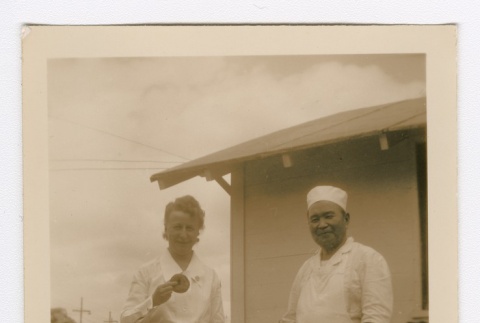 Henrietta Schoen and a man wearing an apron posing with doughnuts (ddr-densho-223-32)