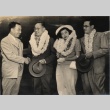 Two men shaking hands, posing with a woman and another man (ddr-njpa-4-4)