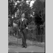 Man in suit standing by metal fence (ddr-densho-426-2177)