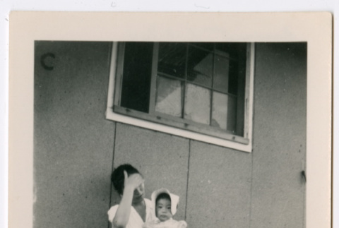 Woman holding toddler girl sitting outside barracks (ddr-densho-329-1276)