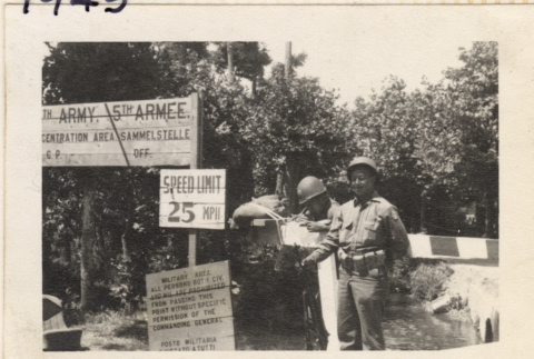 Two men by gate at entrance to P.O.W. Camp (ddr-densho-466-367)