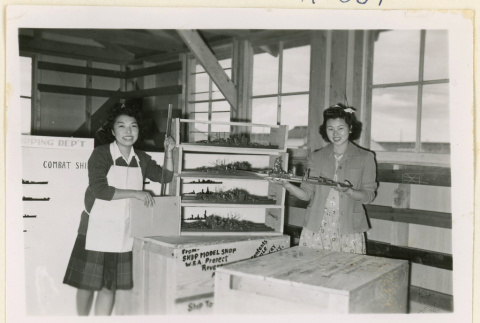 Women pose with ship models at a shipping department (ddr-densho-37-1259)