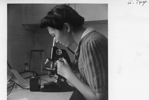 Torako Doi looking through a microscope (ddr-fom-1-853)