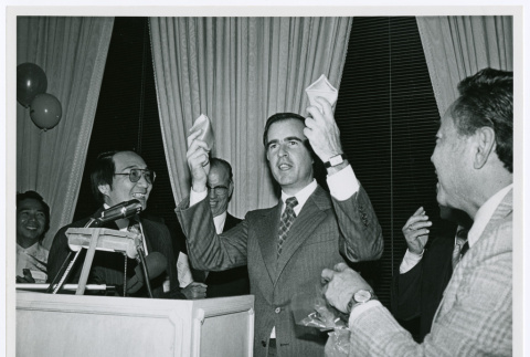 Jerry Brown holding up a broken fortune cookie (ddr-densho-499-32)