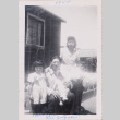Couple with young girl and baby sitting outside barracks (ddr-densho-464-38)