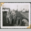Two men leaning on sign by fire hydrant (ddr-densho-434-374)