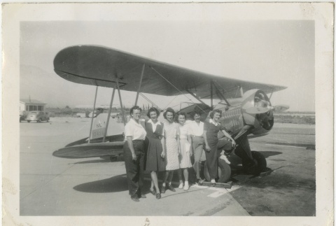 Women standing in front of a biplane (ddr-manz-7-99)