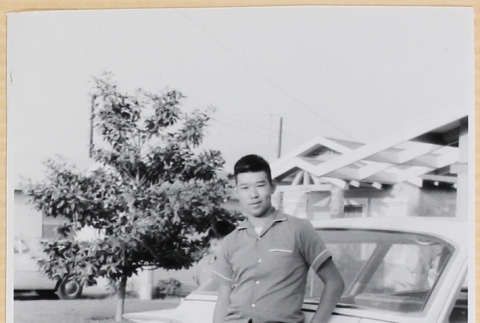 Young man standing by car in driveway (ddr-densho-522-25)