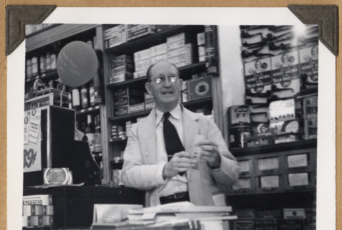Man behind counter at The Owl Drug Co. (ddr-densho-542-101)