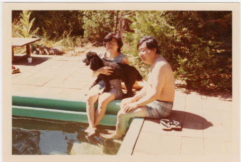 Tomoye and Henri Takahashi by swimming pool, holding dog (ddr-densho-426-1103)