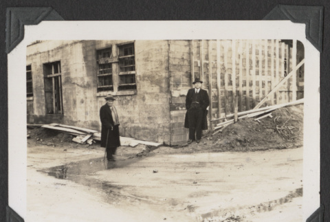 Two men stand at the corner of the new temple building (ddr-sbbt-4-80)