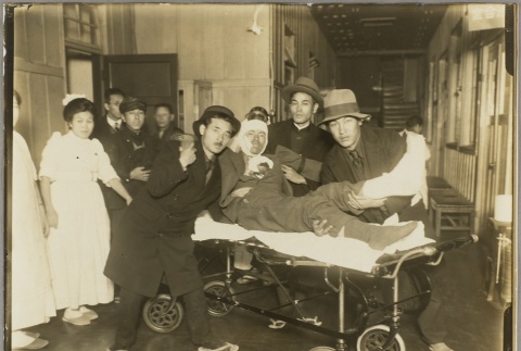 Men helping an injured man off a stretcher (ddr-njpa-13-1460)