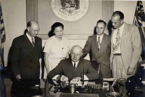 Ingram Stainback signing a document, Oren E. Long and others looking on (ddr-njpa-2-1184)