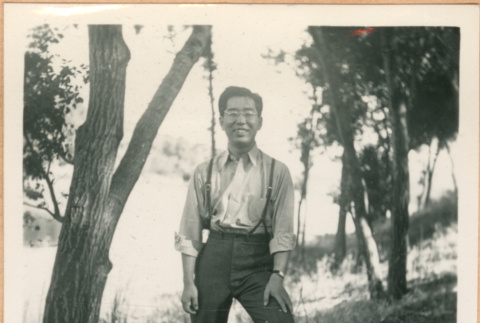 Henri Takahashi posing next to tree (ddr-densho-410-557)