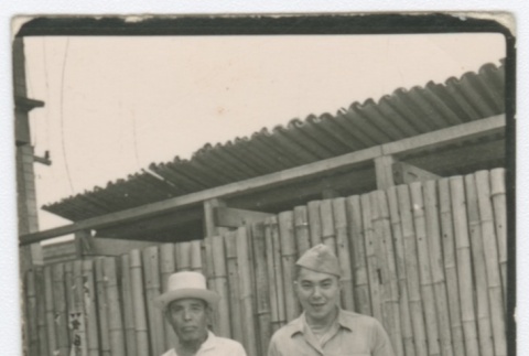 Two men standing in front of bamboo fence (ddr-densho-332-25)