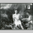 Photograph of a woman sitting on a rock in front of the Manzanar hospital (ddr-csujad-47-256)