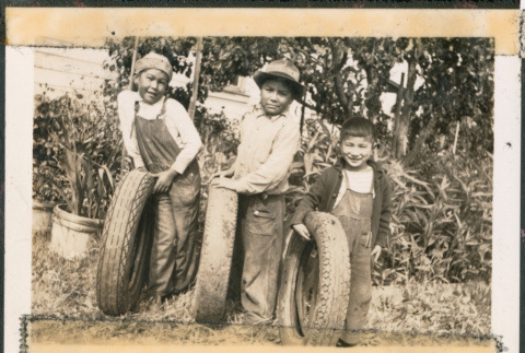 Paul Ima with two unidentified boys with car tires (ddr-densho-483-1042)