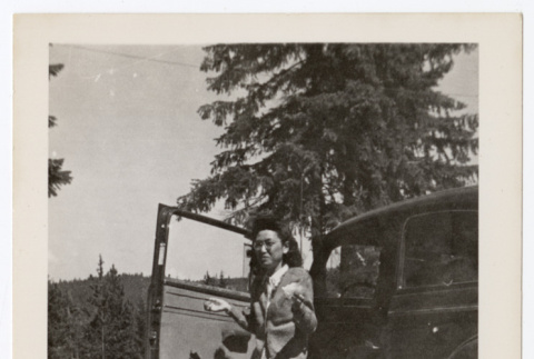 Woman shrugging by a car (ddr-densho-404-416)