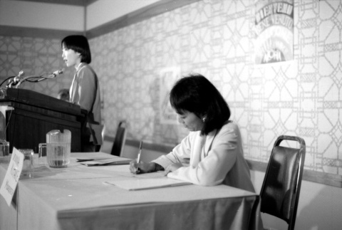 Donna Kotake writing as Wilma Chan speaks (ddr-densho-1007-521)
