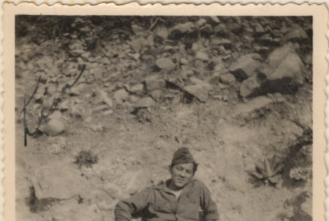 Man leaning against rocky hillside (ddr-densho-466-358)
