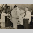 Two men shaking hands while workers unload sacks of rice (ddr-njpa-2-228)