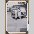 Man and woman lean against a car (ddr-densho-542-75)