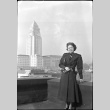 Tomoye (Nozawa) Takahashi standing with large building in background (ddr-densho-426-1764)