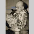 A man wearing leis, holding a cat and smoking a pipe (ddr-njpa-1-2470)