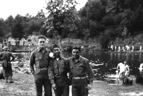 Three men by river with men bathing in background (ddr-ajah-2-753)