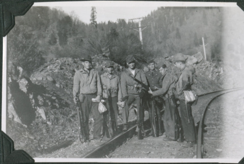 Six men standing by train tracks (ddr-ajah-2-313)