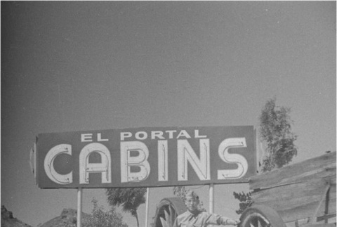 Man in front of a cabin sign (ddr-densho-153-316)