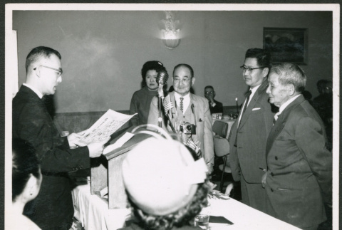 Man at podium reading a document (ddr-densho-293-175)