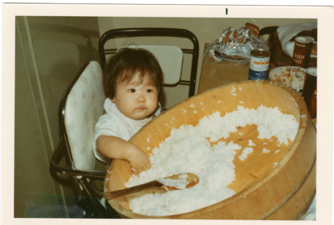 Baby in high chair with large container of rice (ddr-densho-430-193)