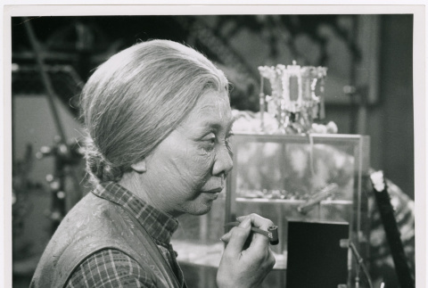 Mary Mon Toy profile holding pipe on set of Kojak episode (ddr-densho-367-361)