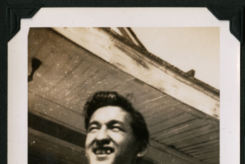 Walter Matsuoka smiles while holding a yearbook (ddr-densho-390-75)