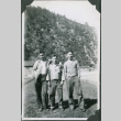 Three men standing with buildings and hill in background.  Joe Iwataki on right (ddr-ajah-2-336)