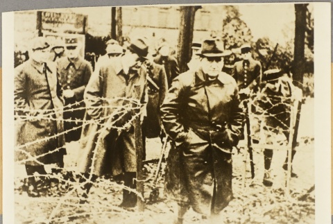 Men passing through an opening in a barbed wire fence (ddr-njpa-13-1313)