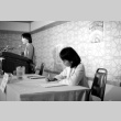 Donna Kotake writing as Wilma Chan speaks (ddr-densho-1007-521)
