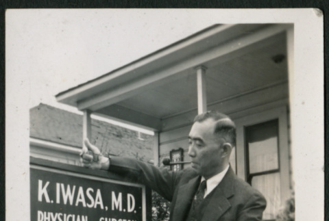 Doctor poses with his office sign (ddr-densho-359-1013)