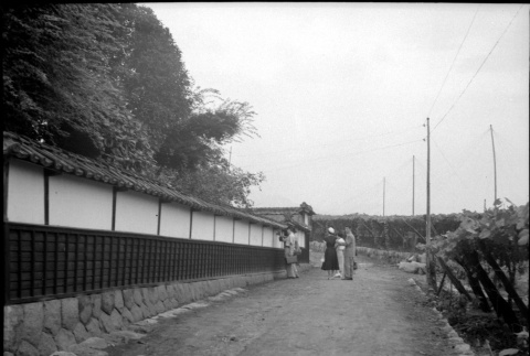 Group standing on dirt road outside wall (ddr-densho-426-2479)