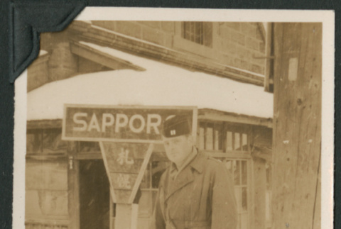 Soldier poses by sign (ddr-densho-397-180)