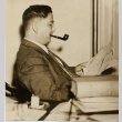 Man smoking a pipe and reading at his desk (ddr-njpa-2-541)